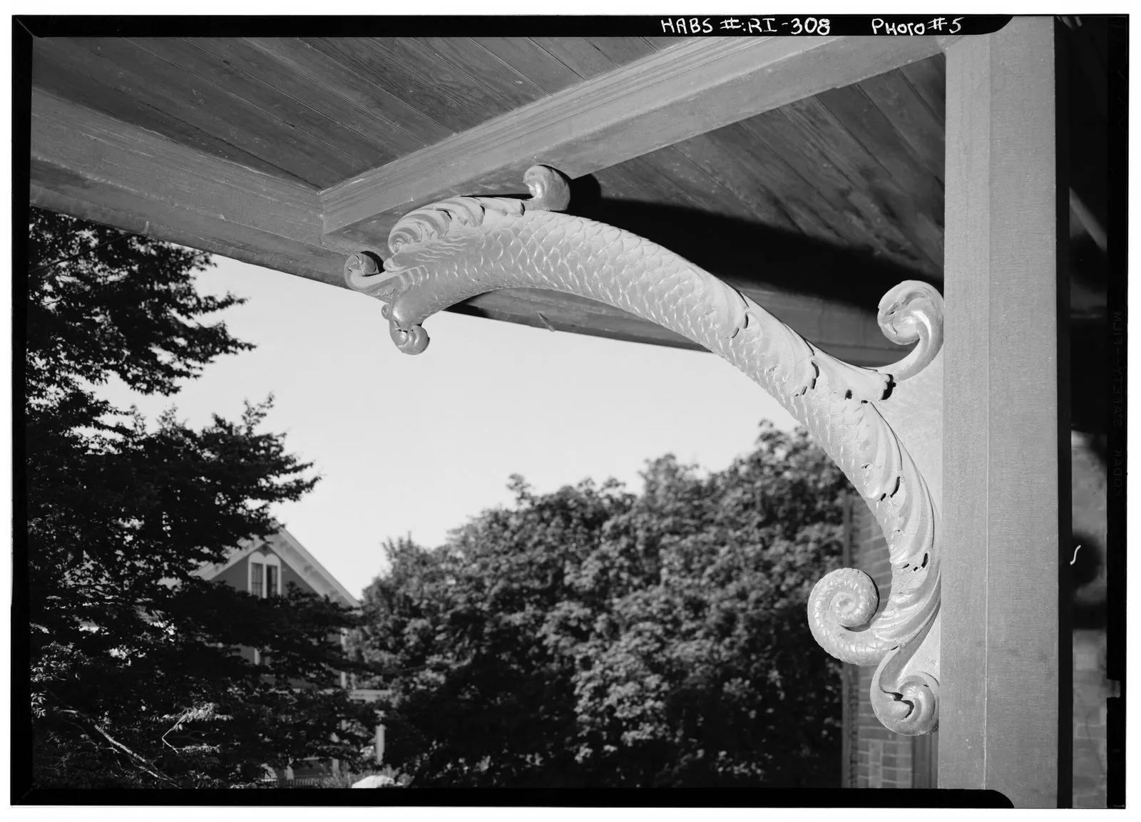 The carved bracket under a porch roof, seen from below.